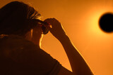 Fototapeta Tęcza - Woman is looking on solar eclipse through three sunglasses. Sun eclipse concept.