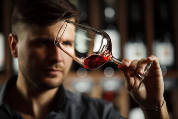 Wall Mural - Bokal of red wine on background, male sommelier appreciating drink