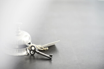 A shiny silver metal bell at the hotel reception. A table in the hotel at the concierge with a bell and a door key. Key and bell in a hotel.