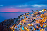Fototapeta Uliczki - Famous greek iconic selfie spot tourist destination Oia village with traditional white houses and windmills in Santorini island in the evening blue hour, Greece
