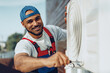 © fotofabrika - Young black man repairman checking an outside air conditioner unit