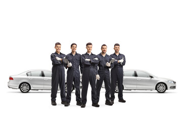 Wall Mural - Five auto mechanic workers in uniforms standing in a group in front of silver cars