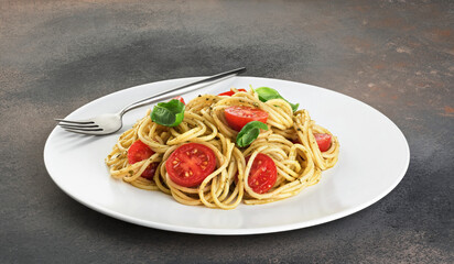 Pasta with pesto sauce, tomatoes and basil.