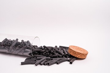 Poster - Closeup shot of raw black penne pasta scattered out of a glass jar isolated on a white background