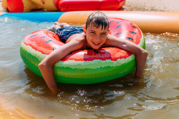 Happy little boy in swimming glasses, swimming in the pool on an inflatable circle. Summer holiday