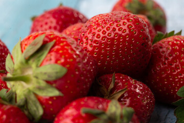 Fresh ripe perfect strawberry on blue wooden background. Fresh strawberry as texture background. Natural food backdrop with red berries. Strawberries sale in a food market in summer.