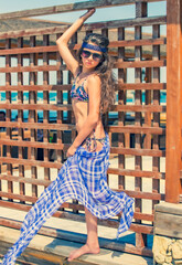 summertime portrait of young girl in a swimsuit standing by the wooden fence