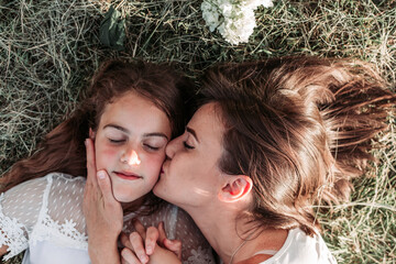 Mom and her daughter lying on the grass, kissing