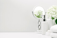 Soft Light Bathroom Decor For Advertising, Design, Cover, Set Of Cosmetic Bottles, White Flowers, Bath Accessories, Mirror, Towel On White Background. Mock Up, Copy Space