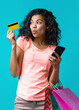 © wpadington - Vertical shot of beautiful female fashion blogger posing over blue background holding credit card and mobile phone in hands