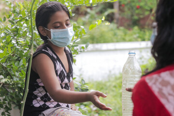 masked girl playing outdoor while keeping social distance during the global pandemic.