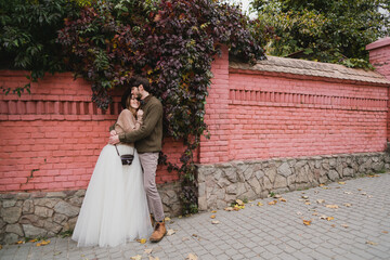 Romantic and happy caucasian couple in casual wedding clothes walking and hugging at the city streets. Love, relationships, romance, happiness, urban concept. Man and woman celebrate their marriage.