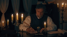 Man In The 18th Century Writing At His Desk Using A Quill Pen