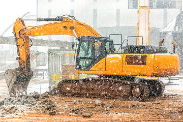 The excavator excavation at the cold weather also snowing in the construction site.