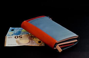 female wallet with 50 euro and 20 euro banknotes on a black background