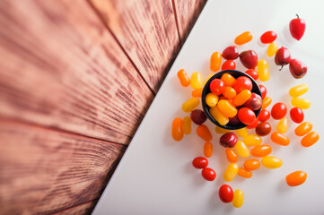 Various colorful cherry tomatoes on white and wooden background. Creative design, beautiful lighting.