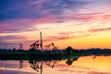 Wall Mural - Oil Pumping Unit by the lake in the sunset.