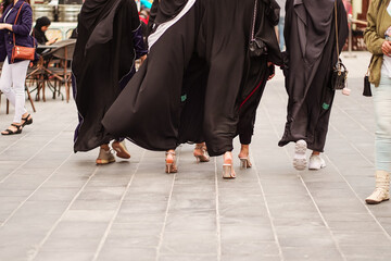 detail of designer heeled shoes worn by unrecognizable Muslim women wearing black abaya in downtown Doha at Souq Waqif