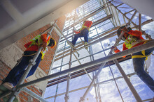 Construction Workers In Safety Uniform Install Reinforced Steel Scaffolding At Outdoor Construction Site.