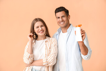 Wall Mural - Young couple applying sunscreen cream against color background