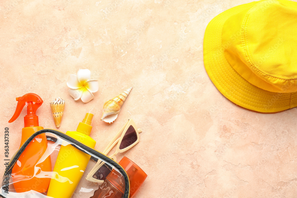 Bag with sunscreen cream, hat and sunglasses on color background