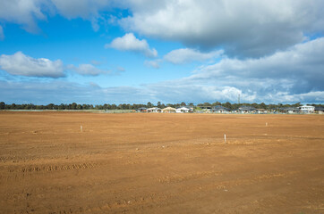 A large vacant land ready to build new residential houses in Melbourne.  Construction site with some Australian homes in the distance.Concept of real estate development and new suburban neighbourhood.