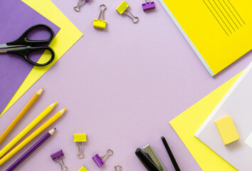 Frame of office and school supplies on a lilac background. Space for text