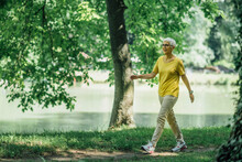 Mature Woman Enjoying Walking Exercise By The Lake