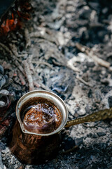 Wall Mural - Boiling coffee in turkish cezva on campfire coals. Luxury camping concept.