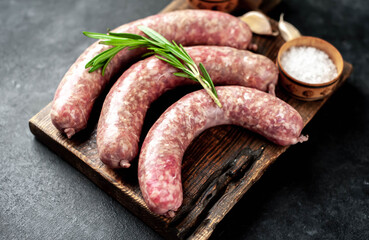 Wall Mural - raw sausages with spices and rosemary on a stone background