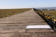 Holzsteg an der Nordsee mit blanko Hinweisschild im Watt bei blauem Himmel