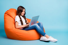 Portrait Of Nice Attractive Lovely Pretty Cute Focused Cheerful Wavy-haired Girl Sitting In Chair Using Laptop Isolated On Bright Vivid Shine Vibrant Blue Teal Turquoise Color Background