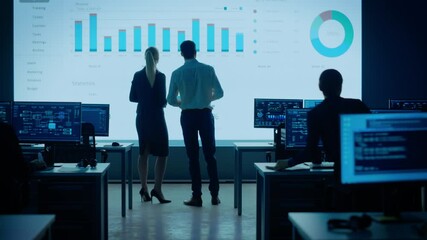 Poster - Project Leader, Chief Executive Discuss Data Shown on Big Display. Screens Show Infographics, Charts, Finance Analysis, Stock Market, Growth.Telecommunications Control Room with Working Professionals