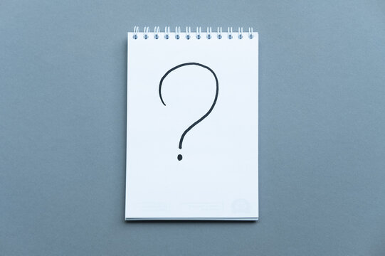 Notebook with the schedule shoot from the top. Spiral notebook blue background. Question mark written in notepad on blue background. Horizontal composition with copy space.