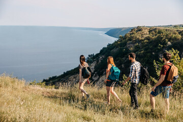 Group of young people hiking in mountains. Tourists with backpacks traveling.