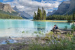 © romylee - Spirit island in Jasper National park and two hikers sitting on a rock