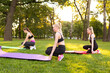 © Bogdan - young people doing aerobics exercises together outdoors in a park  tree women, in a healthy active lifestyle . meditate in the park, relaxation. Pretty woman practicing yoga on the grass