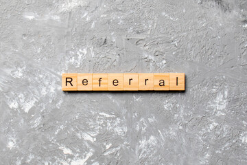 Wall Mural - Referral word written on wood block. Referral text on cement table for your desing, Top view concept