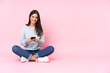 Young caucasian woman isolated on pink background sending a message with the mobile