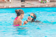 © YouraPechkin - Two cute little sisters girls swim in the pool during vacation on a sunny warm summer day. The concept of the long-awaited vacation. Advertising space
