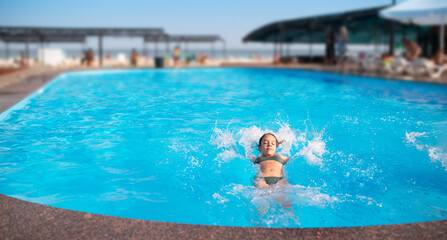 Poster - Top view unidentified pretty young girl happily splashing in blue clear water in the pool under the rays of bright sunlight. Concept of relaxation at the hotel and at sea. Advertising space