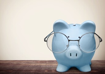 Canvas Print - Blue piggy bank in glasses on the desk