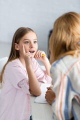 Wall Mural - Selective focus of kid having idea while holding pen near notebook on table and mother