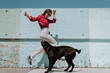 © guille Faingold/Stocksy - Cheerful brunette having fun with her dog outside