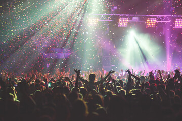 A crowded concert hall with scene stage lights, rock show performance, with people silhouettes during live music show performance with crowd of audience