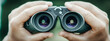 © Nataly - Banner close-up of a hunter man's hands holding binoculars on the blurred background.