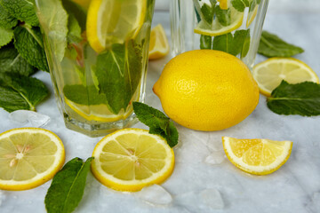 Refreshing drinks for summer, cold sweet and sour lemonade juice in the glasses with sliced fresh lemons. Refreshing summer drink. Traditional lemonade with lemon, mint and ice. Selective focus