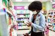 © etonastenka - A dark-skinned girl chooses products in a protective mask. The concept of the coronavirus pandemic and virus protection