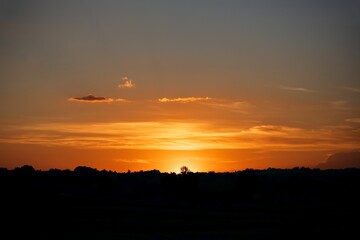 Wall Mural - Orange sunset. Clouds over the contours of forest