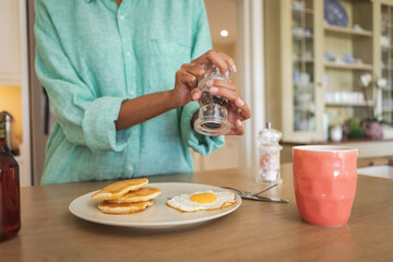 Wall Mural - Mid section of woman putting salt on cooked eggs